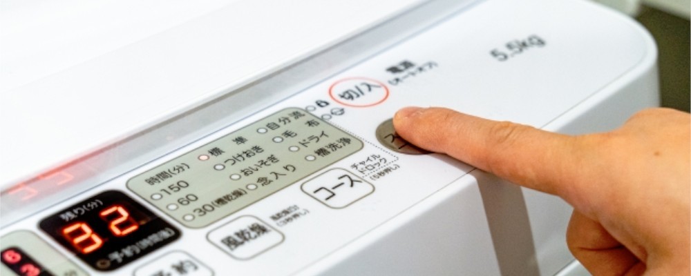縦型洗濯機を操作する手元画像