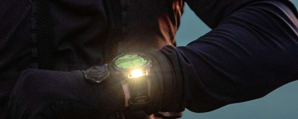 光が反射するガーミン時計を眺める男性の画像