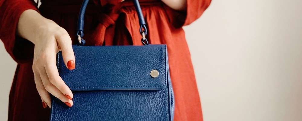 青い革のハンドバッグを持つ女性の画像