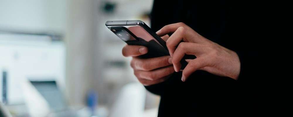 黒いトップスを着た男性がスマートフォンを使う画像