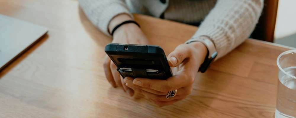 ダイニングテーブルでスマートフォンを操作する人の画像