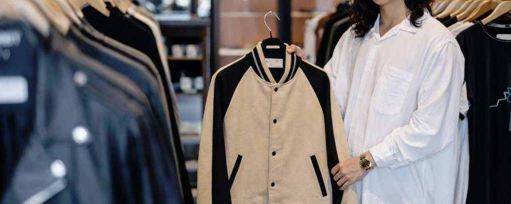 ベージュのブルゾンを持つアパレル店員の画像