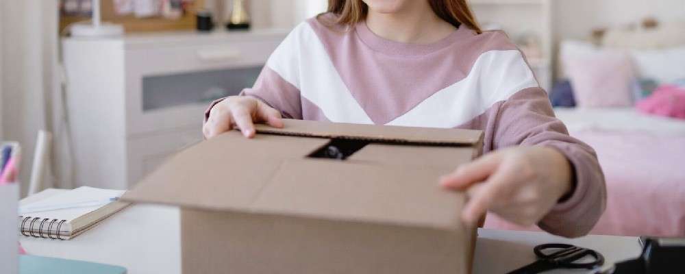 段ボールに洋服を詰める女性