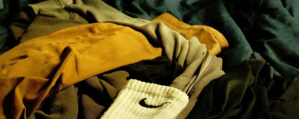 ベッドの上に置かれた服の山の画像