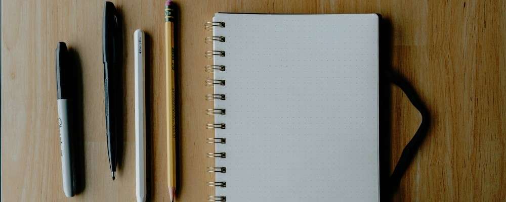 木製の表面にノートと筆記用品の画像