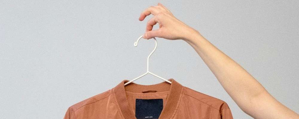 白いハンガーに茶色の長袖シャツの画像