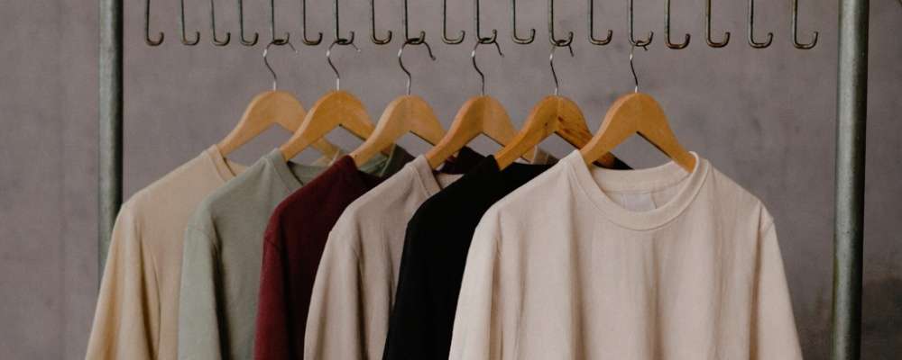 洋服ラックにぶら下がっているtシャツの画像